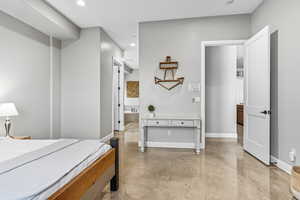 Bedroom with concrete floors, recessed lighting, and connected bathroom