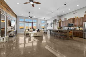 Living room with finished concrete flooring, recessed lighting, and ceiling fan
