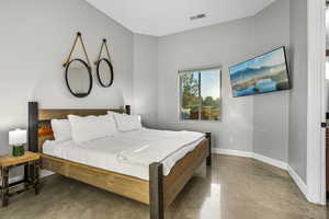 Bedroom with finished concrete floors and baseboards