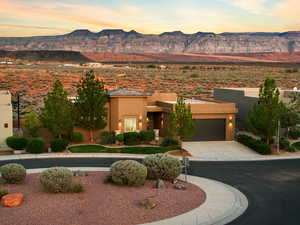 View of front of house with stucco siding, a mountain view, concrete driveway, and a garage
