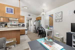 Living area with light colored carpet, vaulted ceiling, light tile patterned flooring, and a chandelier