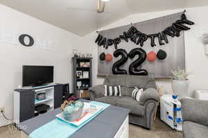 Carpeted living area with lofted ceiling and a ceiling fan