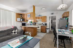 Living area featuring lofted ceiling, a chandelier, light tile patterned floors, and light colored carpet