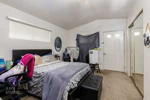 Bedroom with lofted ceiling, light colored carpet, and a closet