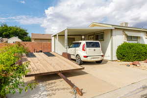 View of front facade featuring a wooden deck, an attached carport, and concrete driveway