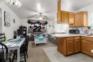 Kitchen featuring lofted ceiling, open floor plan, light countertops, a peninsula, and brown cabinetry