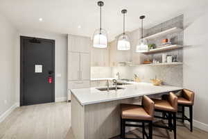 Kitchen with light wood-type flooring, modern cabinets, pendant lighting, open shelves, and a peninsula