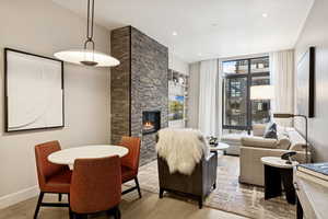 Living area with light wood-style flooring, built in shelves, a stone fireplace, and recessed lighting