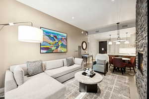 Living area featuring light wood-type flooring, a stone fireplace, and recessed lighting