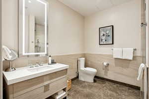 Bathroom with tile walls, vanity, a shower stall, and wainscoting