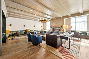 Living area featuring a fireplace, a chandelier, wood-type flooring, plenty of natural light, and a wood ceiling with exposed beams
