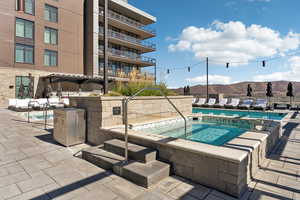 Community pool with a mountain view, a patio area, and a hot tub