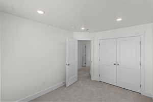 Unfurnished bedroom with light colored carpet, recessed lighting, and a closet