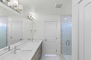 Bathroom with a shower stall, double vanity, and light marble finish floors