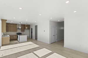 Kitchen with open floor plan, recessed lighting, light countertops, light wood finished floors, and a kitchen island