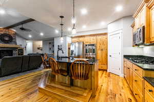 Kitchen with an island with sink, light wood-style floors, open floor plan, a kitchen breakfast bar, and hanging light fixtures