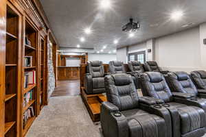 Carpeted home theater with a textured ceiling and french doors