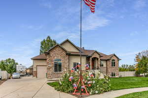 View of front of property with stone siding, stucco siding, concrete driveway, and a garage