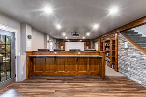 Bar featuring brown cabinets, dark wood-type flooring, stairway, a textured ceiling, and recessed lighting