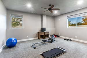 Workout room with a textured ceiling, carpet, and a ceiling fan