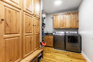 Laundry area with light wood-style floors, washing machine and dryer, and cabinet space