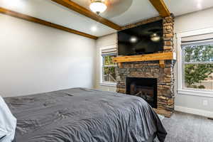 Bedroom featuring beamed ceiling, a fireplace, and carpet floors