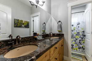 Full bathroom featuring double vanity, a chandelier, and a shower with shower curtain