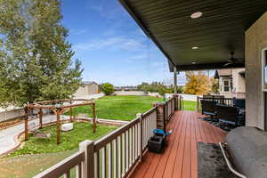 Wooden terrace featuring a fenced backyard, a ceiling fan, area for grilling, and outdoor dining area