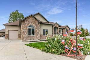 View of front of home featuring stucco siding, a garage, driveway, and stone siding
