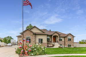 View of front facade with stucco siding, driveway, stone siding, and an attached garage