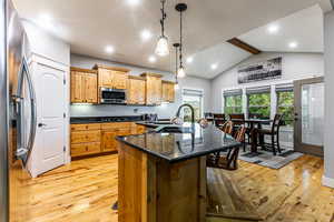 Kitchen with light wood finished floors, stainless steel appliances, recessed lighting, hanging light fixtures, and dark stone countertops