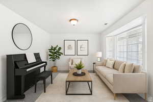 Living area with baseboards and light carpet