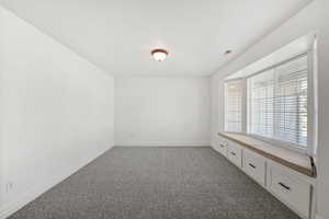 Unfurnished room featuring dark colored carpet and baseboards
