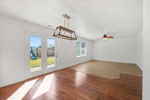 Unfurnished dining area featuring light wood-style flooring, a chandelier, and a ceiling fan