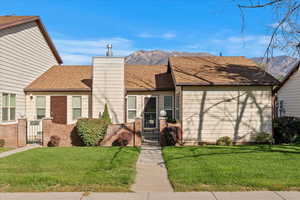 View of front of property with a gate, roof with shingles, a mountain view, and a chimney