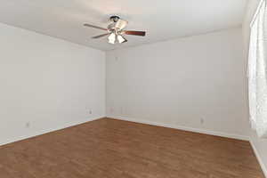 Unfurnished room featuring dark wood-type flooring and ceiling fan