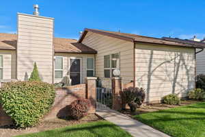 View of front of home with a shingled roof, a gate, and a chimney