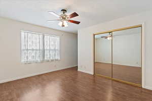 Unfurnished bedroom with a ceiling fan, a closet, a textured ceiling, and wood finished floors