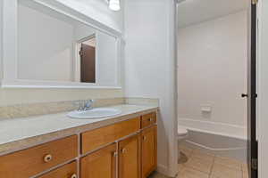 Full bath featuring vanity, light tile patterned flooring, and washtub / shower combination