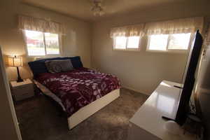 Bedroom with dark colored carpet and ceiling fan