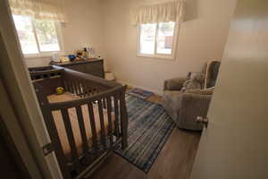 Bedroom featuring dark wood-style flooring and a crib