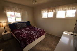 Bedroom featuring dark colored carpet and baseboards
