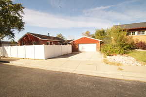 View of front of property featuring brick siding, an outdoor structure, and concrete driveway