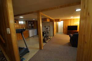Exercise area with wood walls, light carpet, and separate washer and dryer