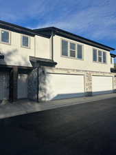 View of front of house featuring stone siding, stucco siding, and a garage