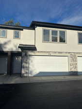 View of side of home featuring stone siding, stucco siding, and a garage