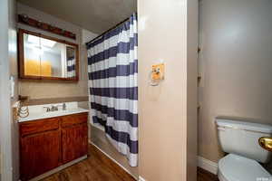 Bathroom with dark wood-style flooring, vanity, shower / bath combo, and a textured ceiling