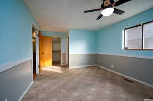 Unfurnished bedroom with light colored carpet, a walk in closet, and a ceiling fan