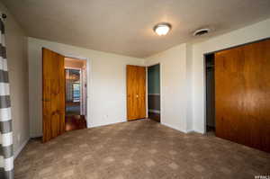 Unfurnished bedroom featuring a textured ceiling, a closet, and carpet