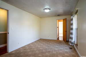 Carpeted spare room featuring a textured ceiling and baseboards